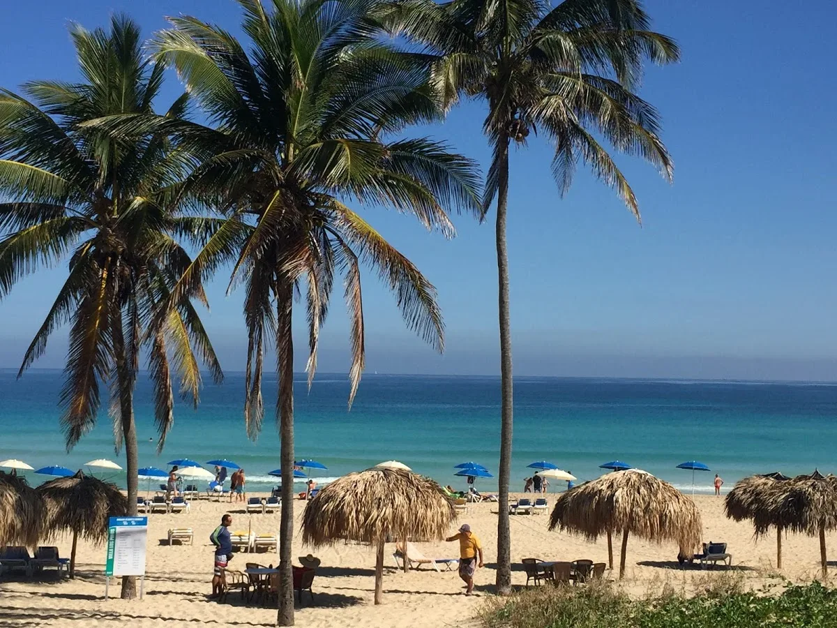 Praia de areia com palmeiras e barracas de palha, em Havana, em 2018.