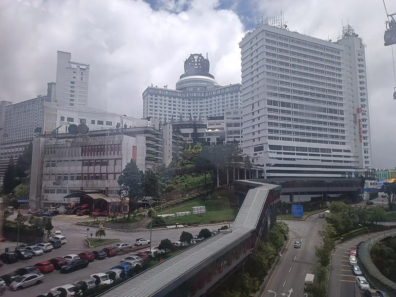 Hotéis brancos altos, um com cúpula, numa encosta acima de um estacionamento.