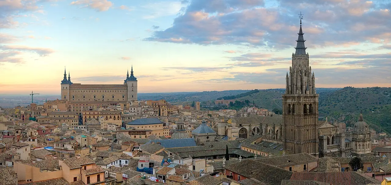 Panorama de Toledo ao amanhecer, com o Alcázar à esquerda, a torre da catedral à direita e telhados de telha por toda a cidade antiga.