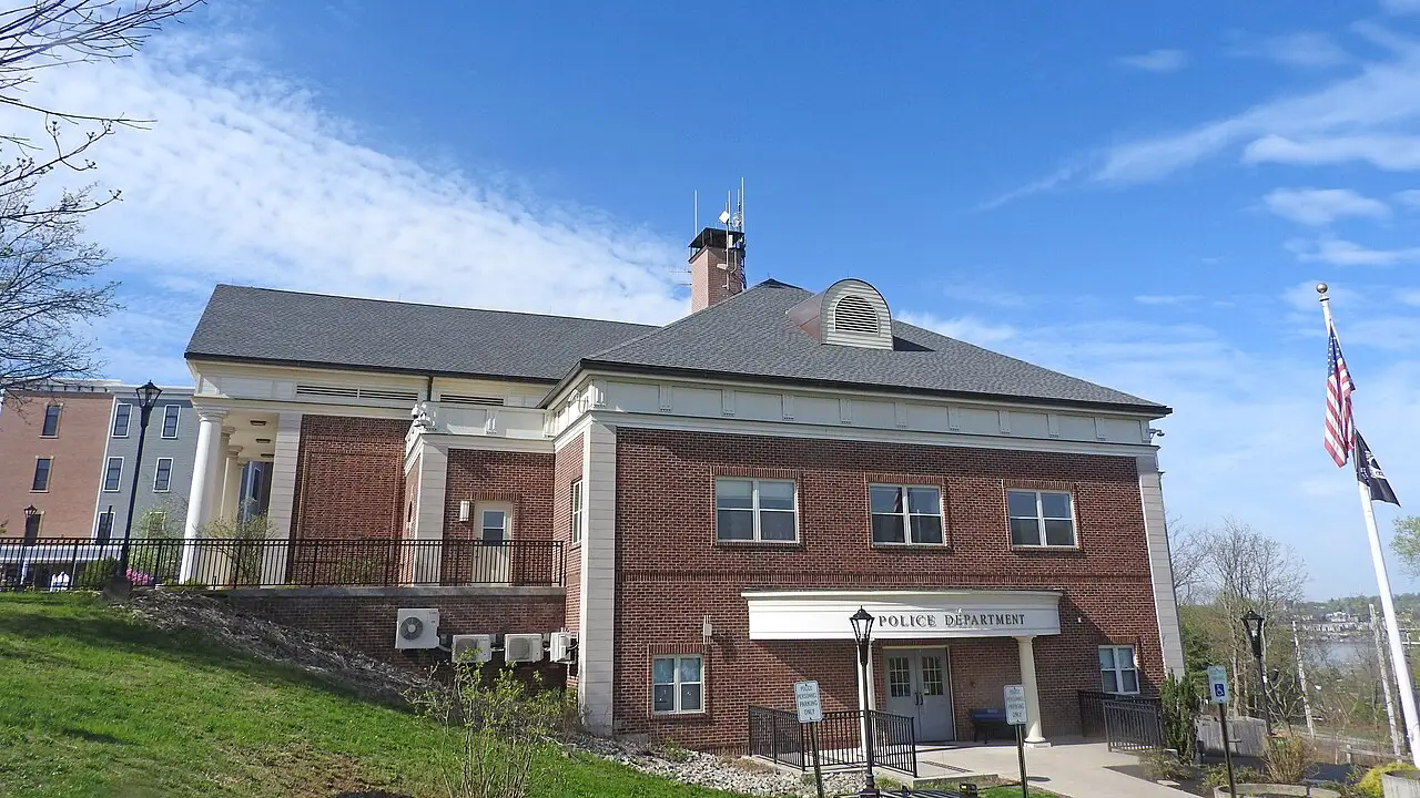 Bâtiment de brique avec l'écriteau du poste de police et le drapeau des États-Unis à côté.
