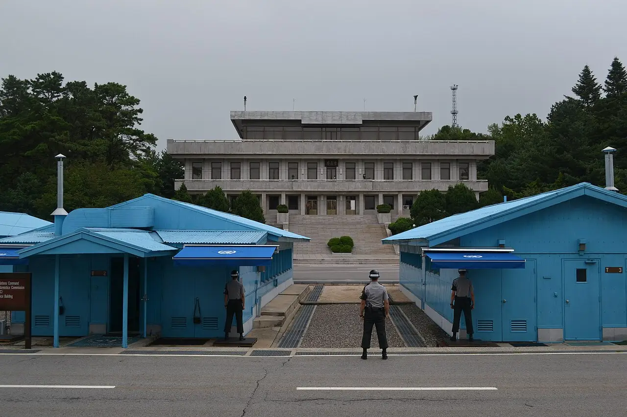 Barracões azuis com toldos da ONU e soldados de guarda em frente a um edifício de concreto de dois andares, na zona desmilitarizada da Coreia.