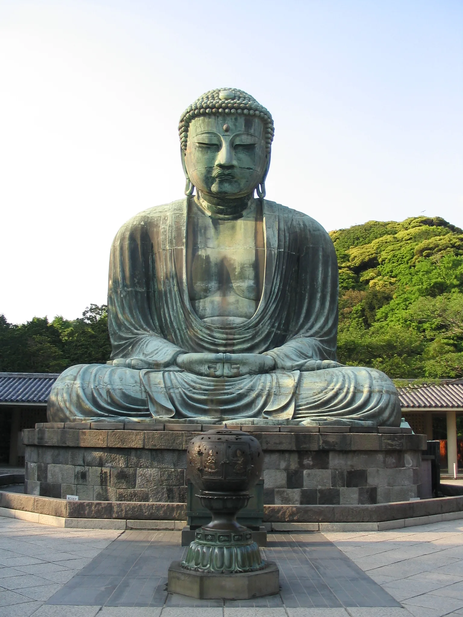 Estátua de bronze do Grande Buda de Kamakura, sentada num pedestal de pedra, vista de frente.