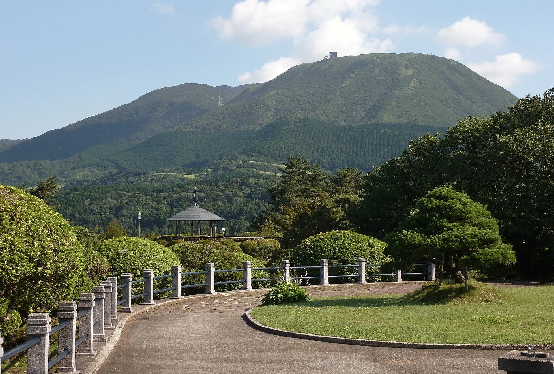 Caminho do parque com uma montanha coberta de mata ao fundo.