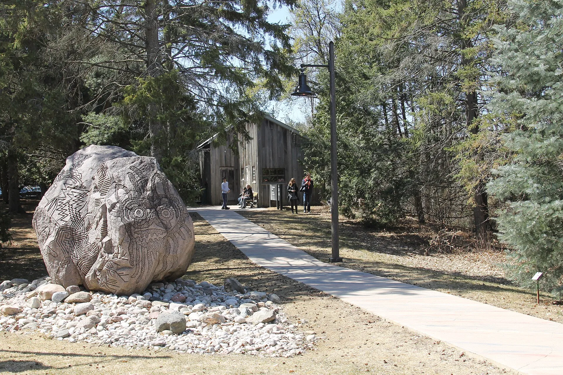 Una piedra grande en el camino y el edificio de la colección entre los árboles.