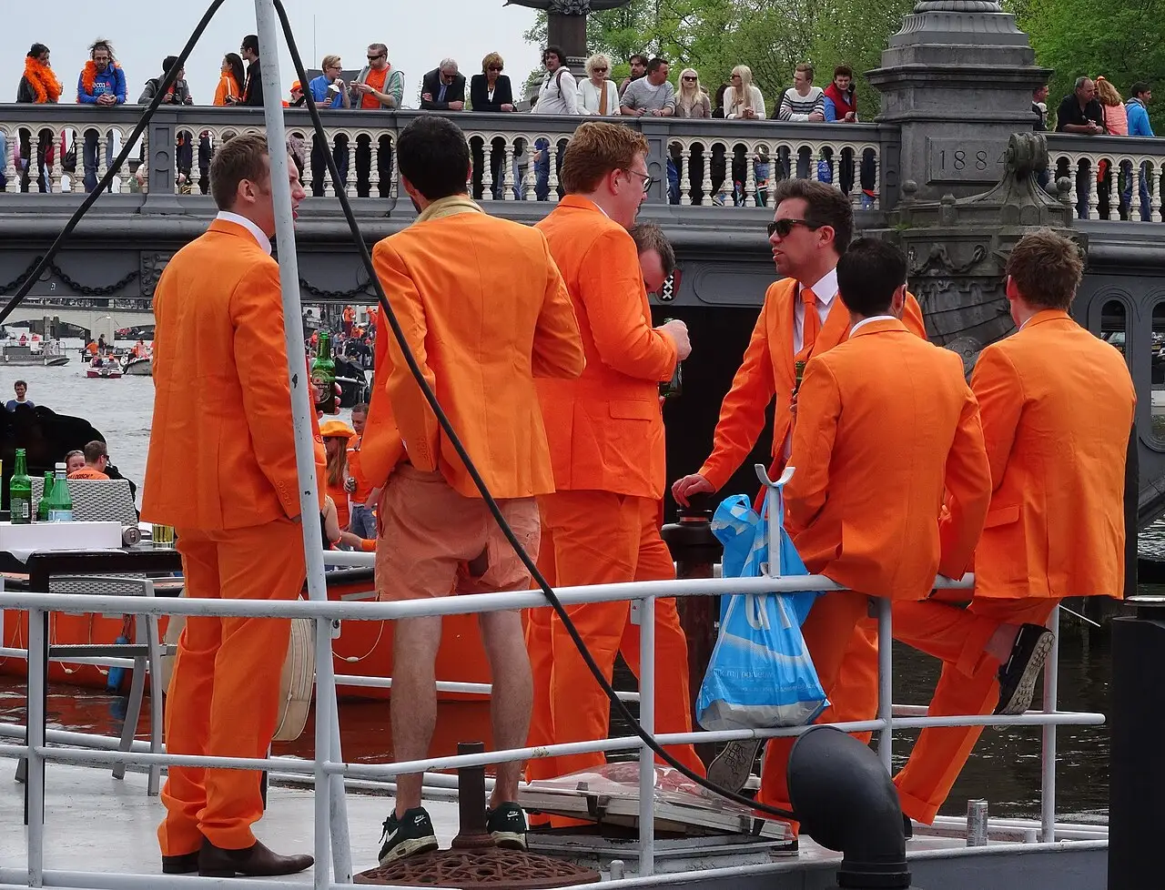 Homens de terno laranja em um barco com grades durante o Koningsdag de 2014 em Amsterdã.