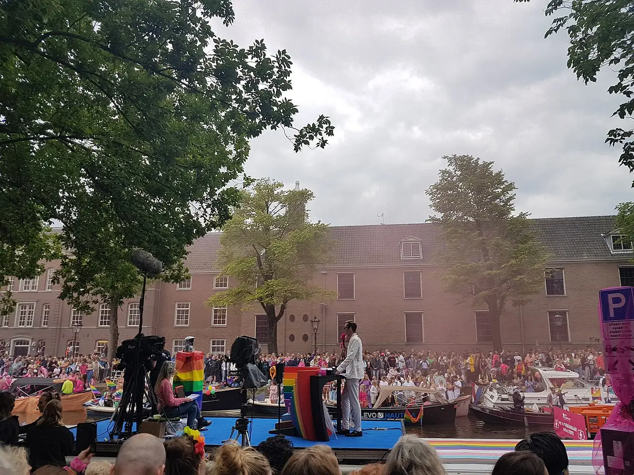Palco montado em uma praça com público diante de um prédio de tijolos e árvores durante a Amsterdam Pride 2023.