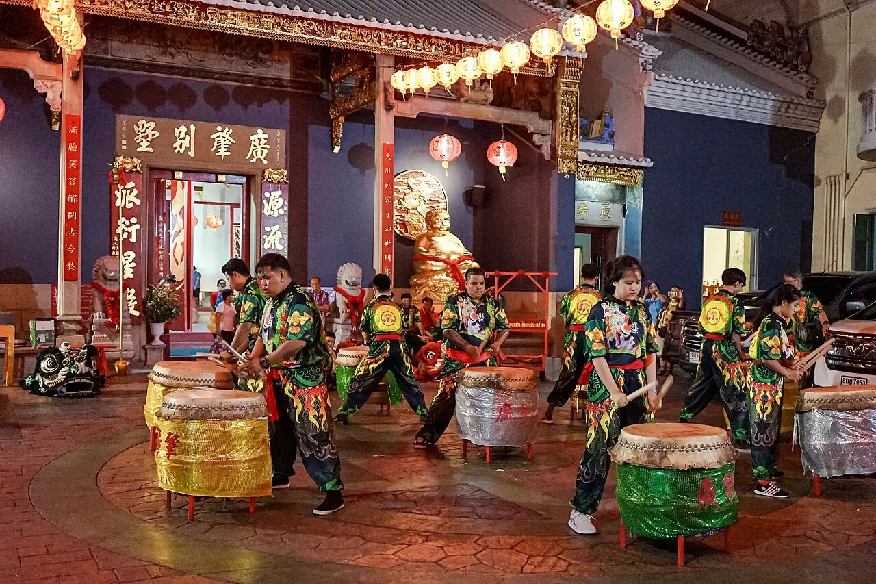 Dança do leão com tambores diante de um santuário chinês decorado com lanternas, à noite, durante o Ano-novo chinês em Bangkok.