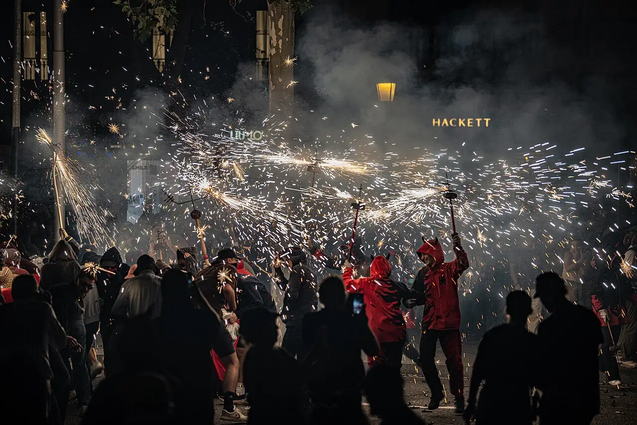 Multidão à noite em meio a faíscas de fogos do correfoc da festa da Mercè, em Barcelona.