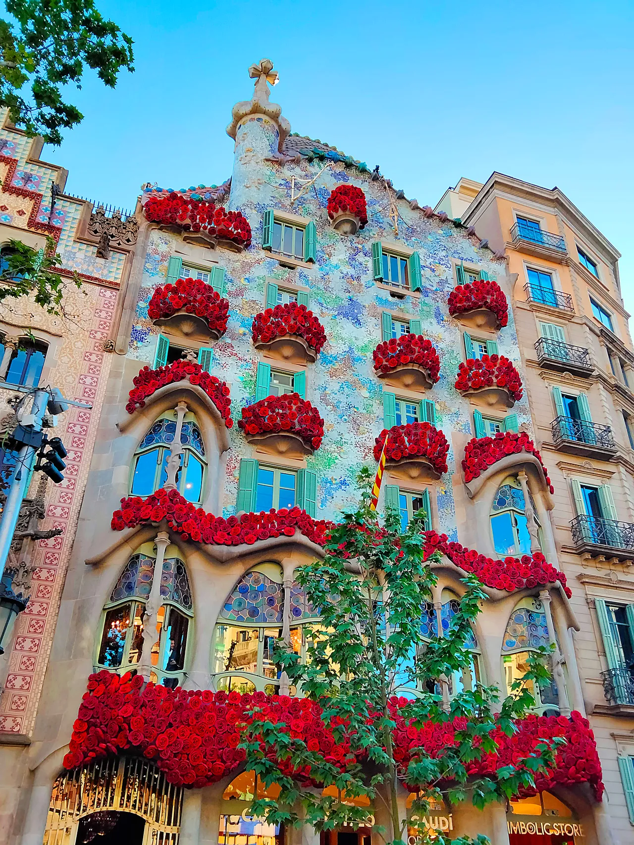 A fachada da Casa Batlló, no Passeig de Gràcia, com buquês de rosas vermelhas nas janelas e uma faixa de rosas no térreo, no Sant Jordi de 2025.