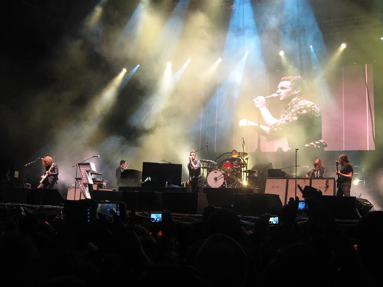 Banda em um palco com luzes azuis e amarelas e fumaça no Festival Estéreo Picnic de 2013, em Bogotá.