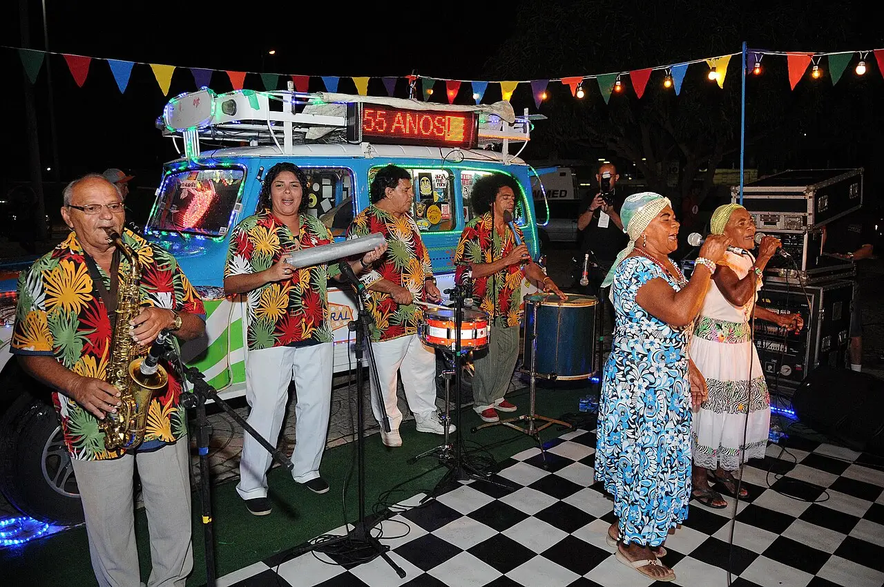 Banda toca à noite diante de um trailer azul com bandeirolas e o número 55 anos, na comemoração dos 55 anos de Brasília.