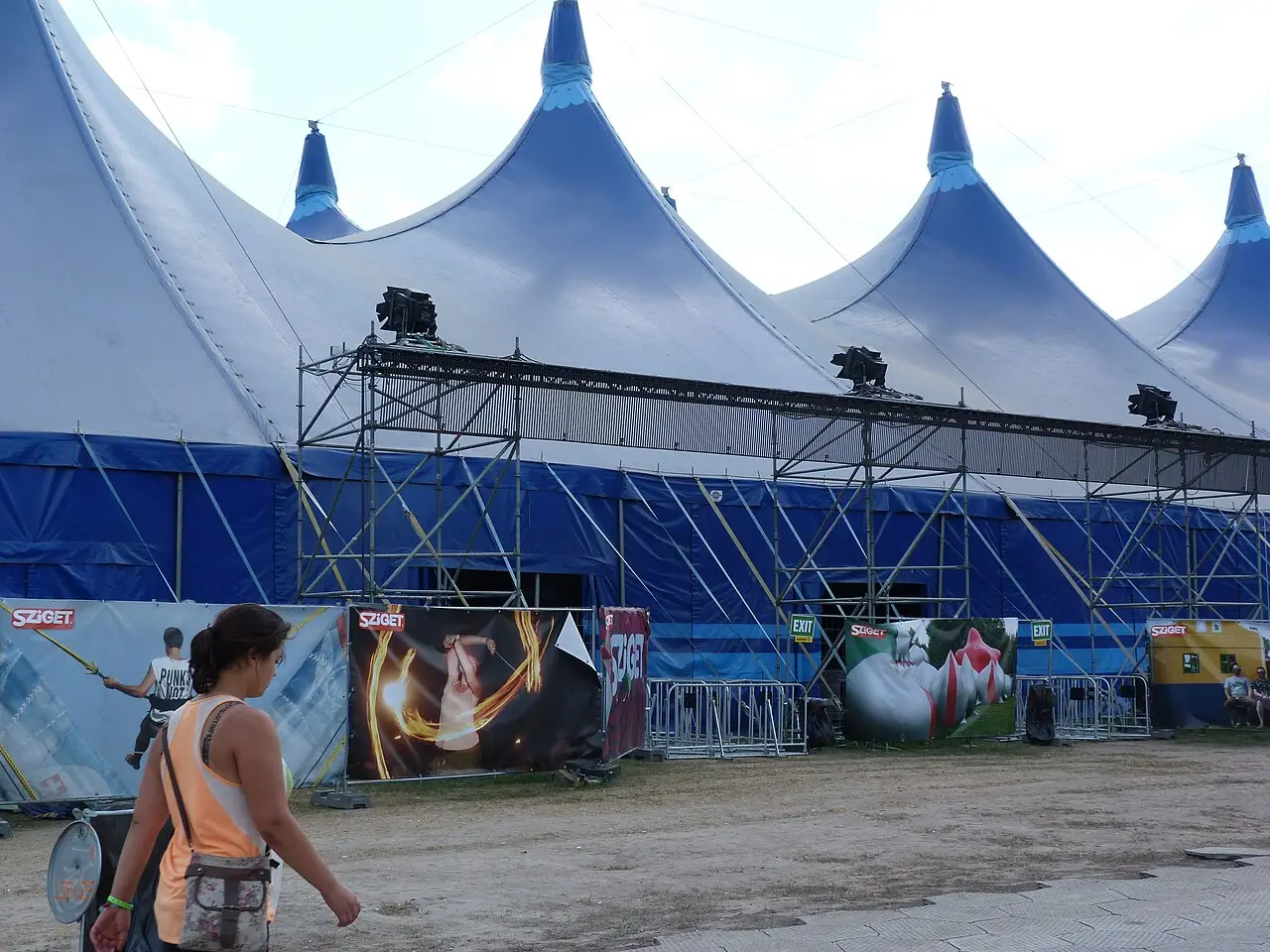 Grande tenda azul e branca com entradas e uma área de terra em frente, durante o Sziget de 2012 em Budapeste.