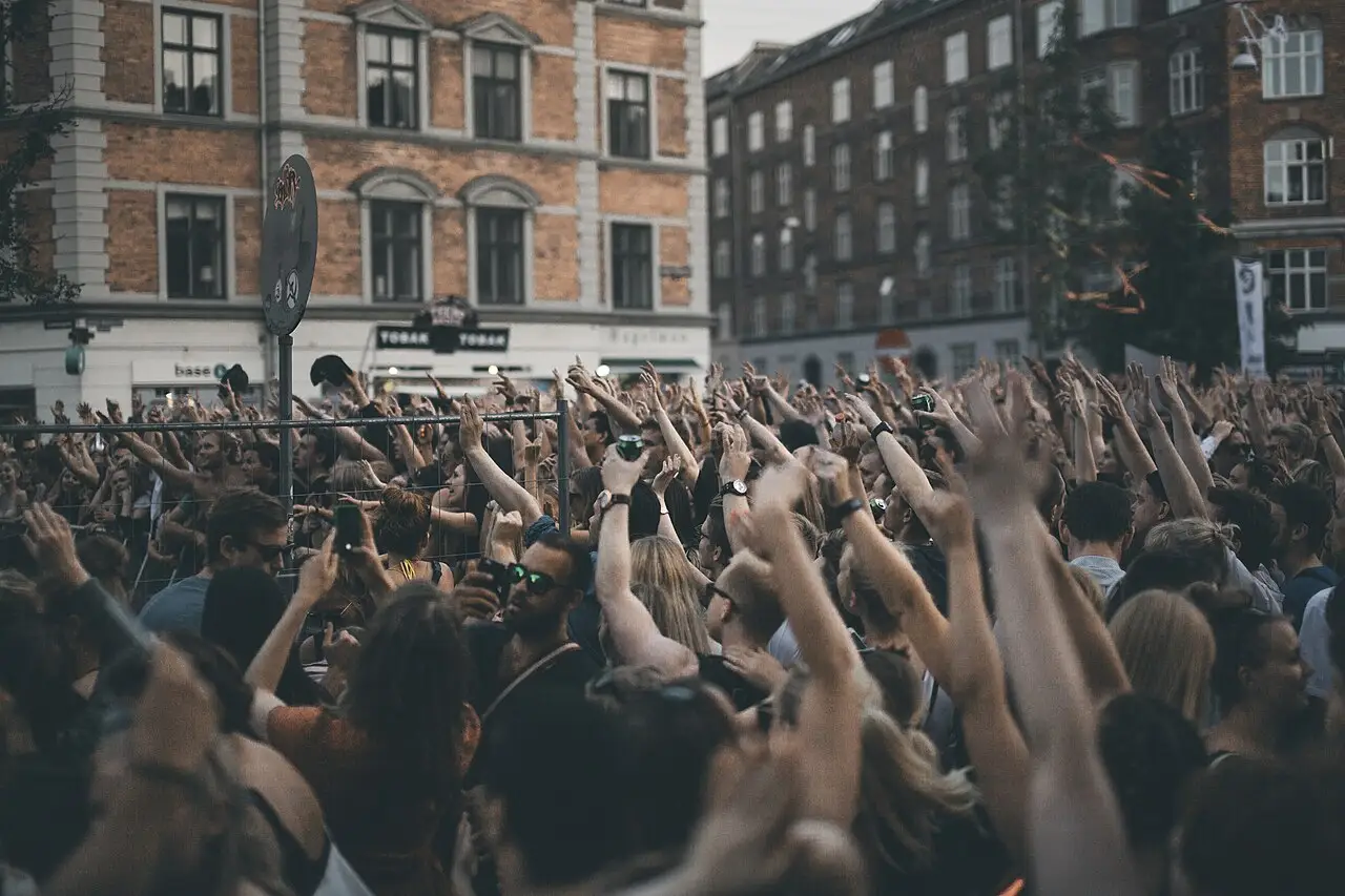 Multidão de braços erguidos em uma rua de Copenhague, com prédios de tijolo ao fundo, no Distortion de 2016.