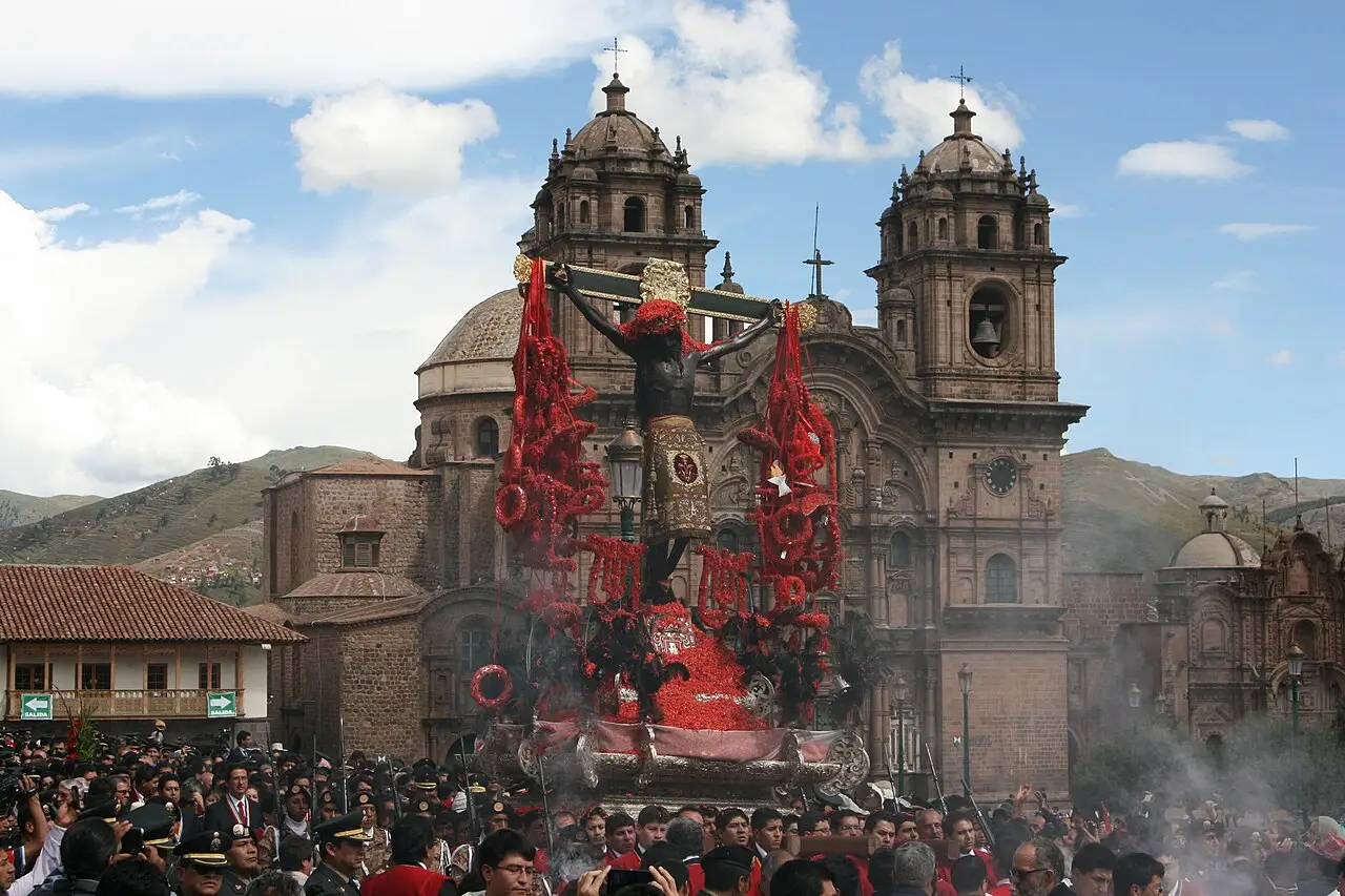 Procissão do Señor de los Temblores na Plaza de Armas de Cusco, com o Cristo entre flores vermelhas e a multidão diante da igreja.