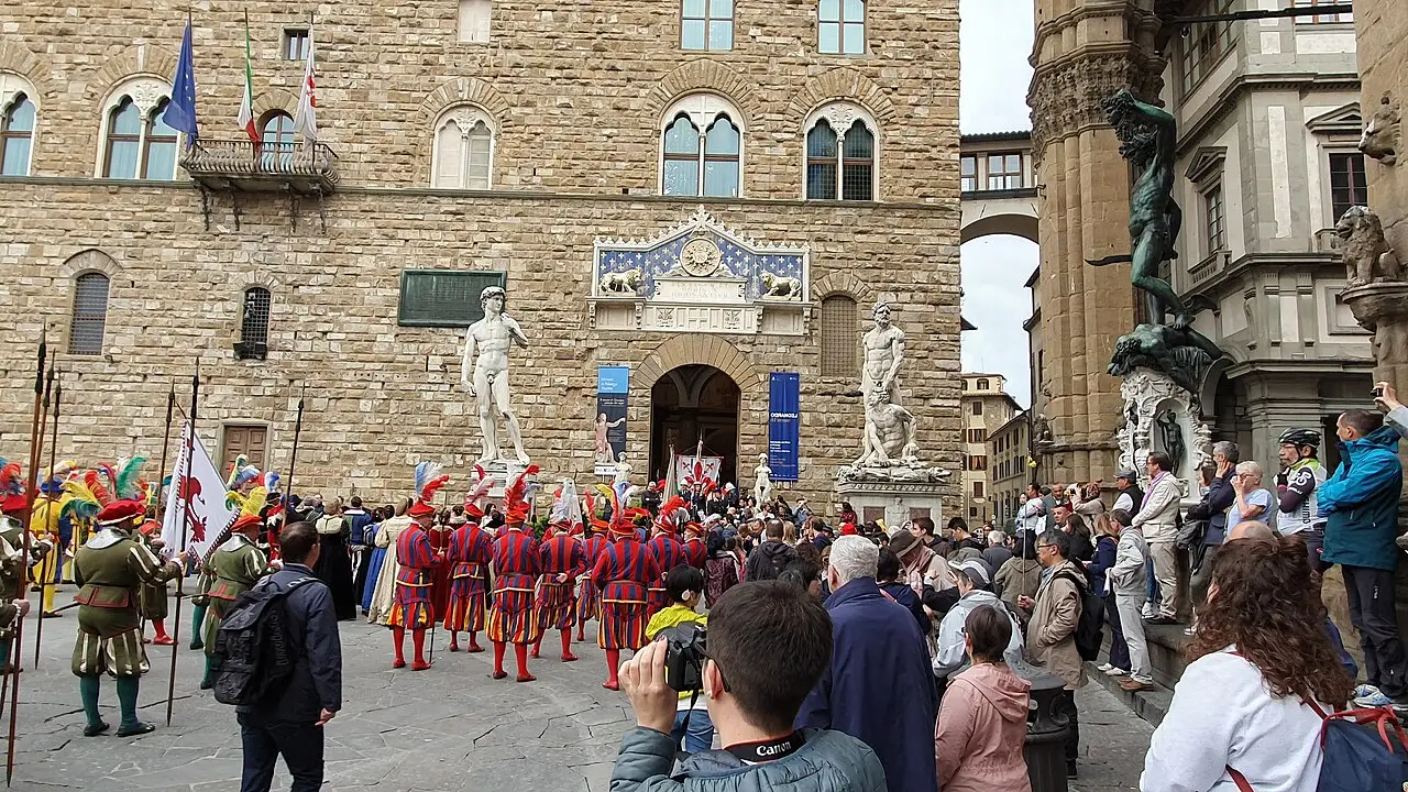 Personnes en costumes historiques rouges et verts rassemblées devant le Palazzo Vecchio, à Florence, avant le Scoppio del Carro de Pâques.
