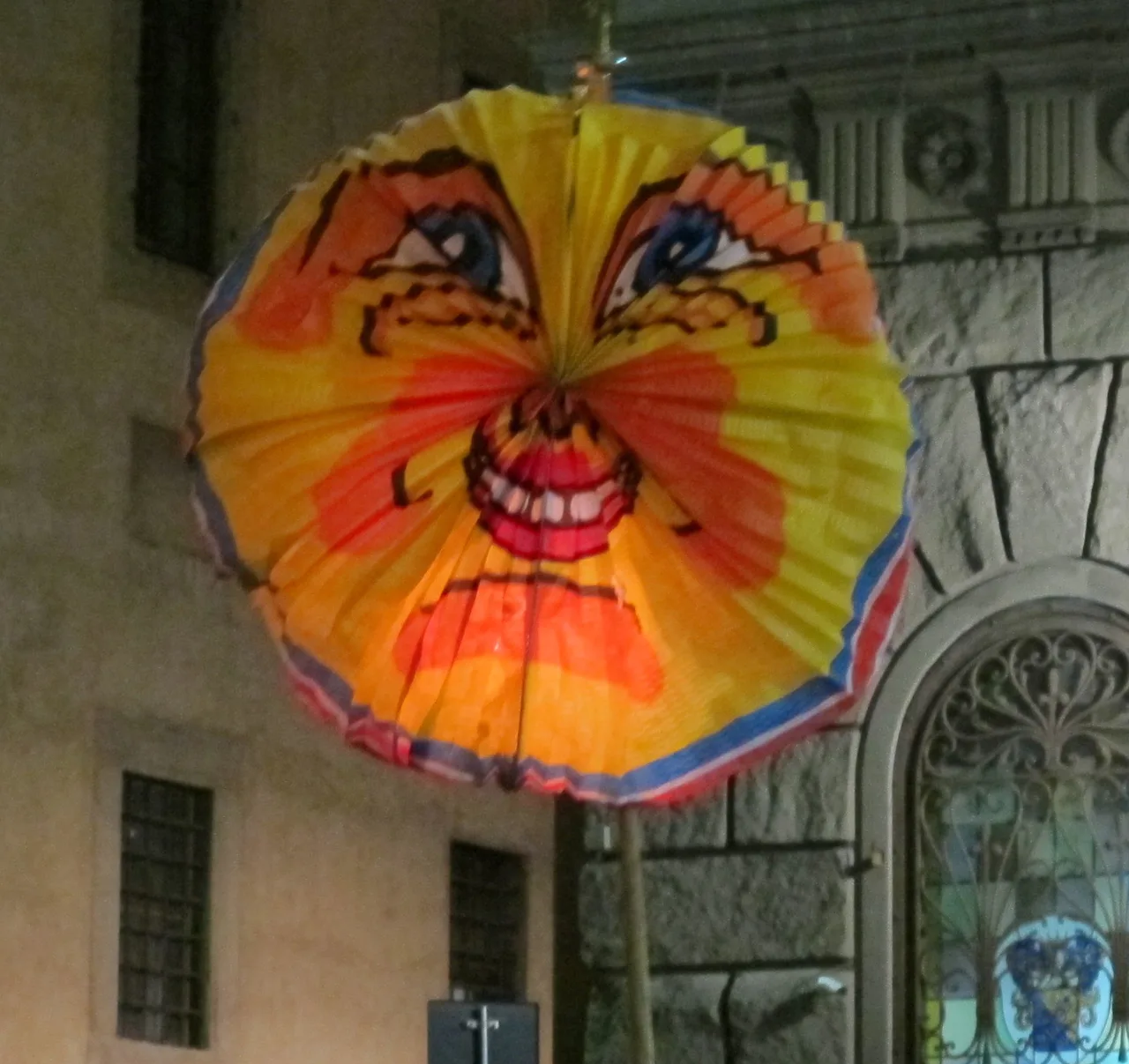 Lanterne ronde en papier plissé, peinte en jaune, orange et rouge, suspendue devant une façade de pierre à la Festa della Rificolona de 2011, à Florence.