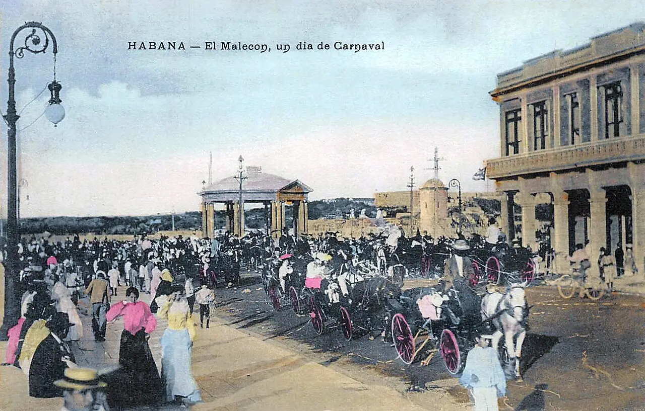 Cartão-postal antigo colorido do Malecón em dia de carnaval, com multidão a pé e carruagens enfileiradas diante de edifícios de arcadas.