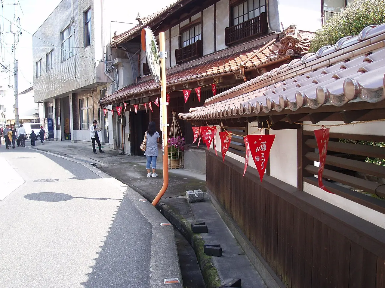 Rua das cervejarias de saquê em Saijō, com bandeirolas vermelhas entre fachadas baixas durante o festival de 2009.
