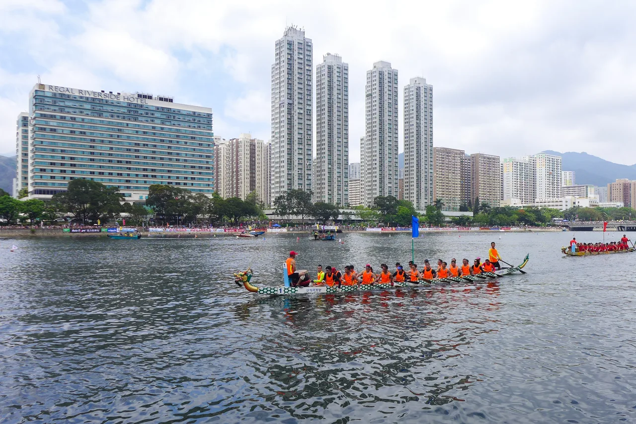Barcos-dragão alinhados no rio Shing Mun, em Sha Tin, com torres e um hotel ao fundo, na prova de 30 de maio de 2017.