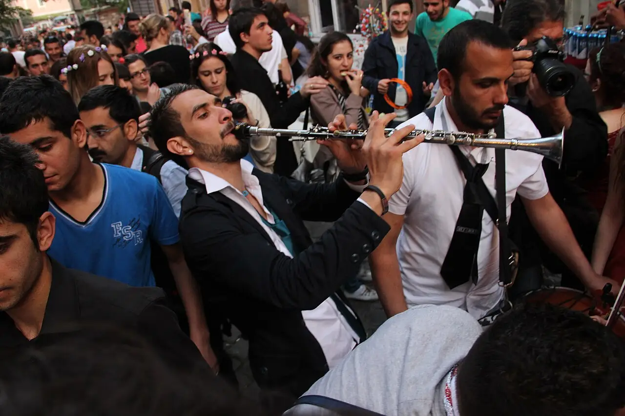 Músico tocando clarinete no meio de uma multidão apertada de jovens, durante a festa de Hıdırellez no bairro de Ahırkapı, em 2013.