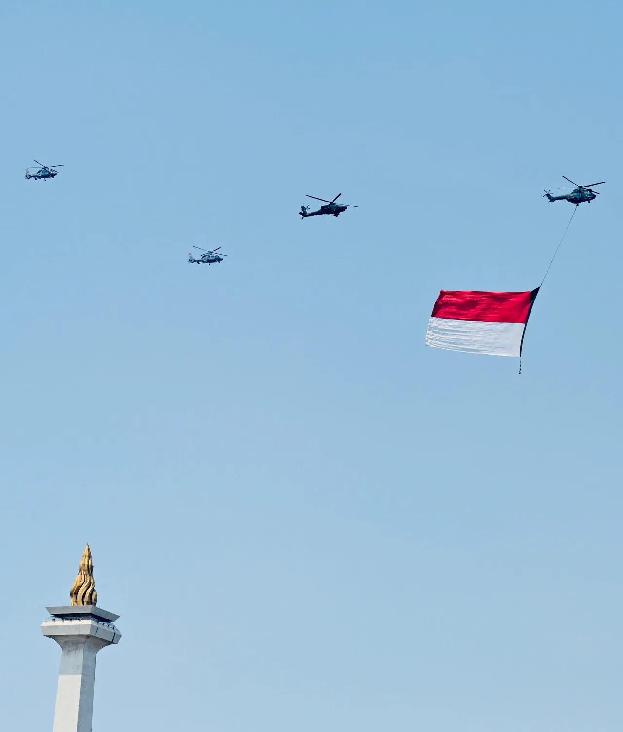 Helicópteros sobre o Monas, um deles rebocando a bandeira da Indonésia, no desfile aéreo do 78º aniversário da independência, em 17 de agosto de 2023.