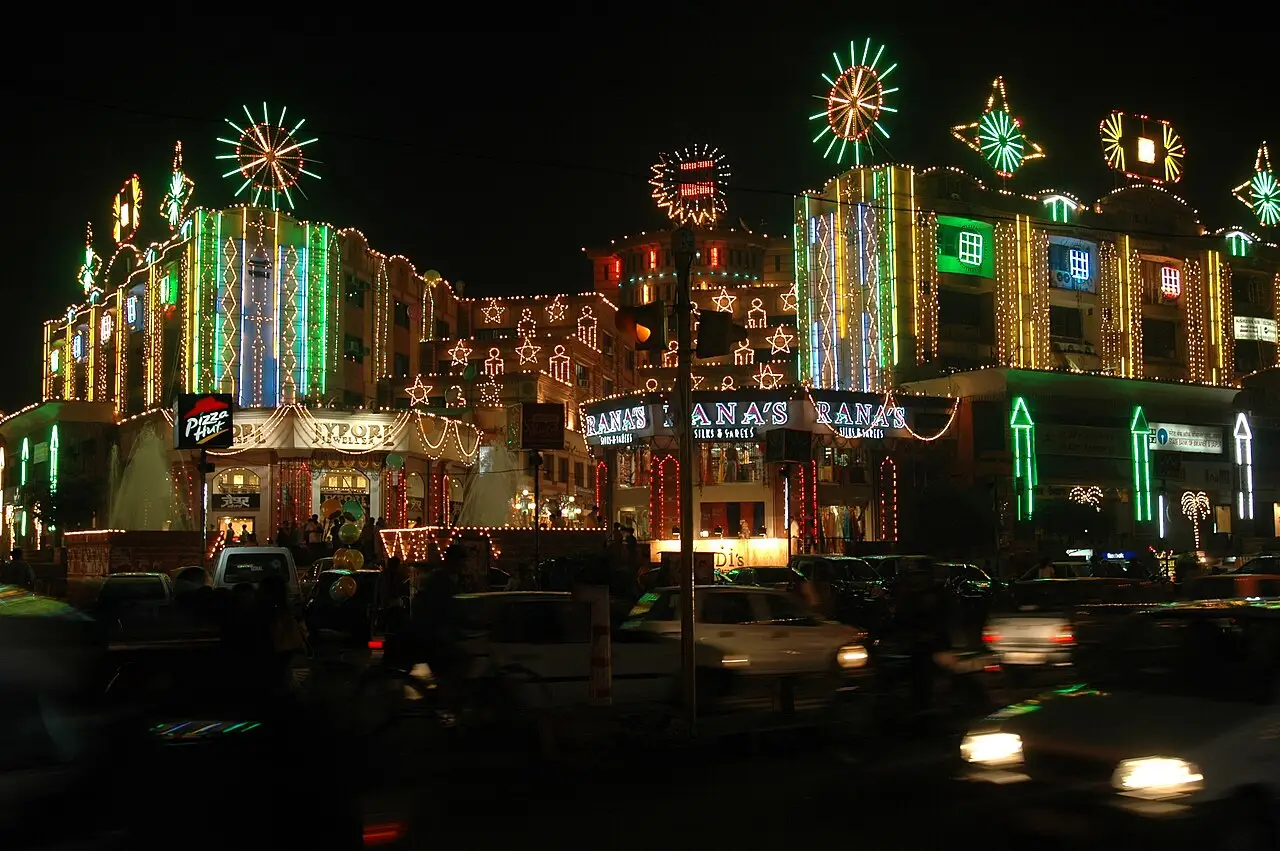Edifícios e postes cobertos por fileiras de luzes verdes, brancas e vermelhas em uma rua de Jaipur à noite, na época do Diwali.