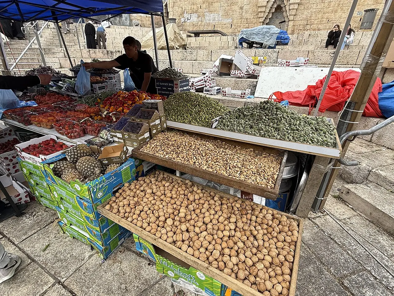 Banca de mercado com caixas de nozes e frutos secos sob uma lona azul, em Jerusalém Oriental, durante o mês do Ramadã.
