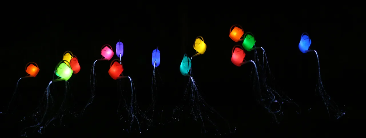 Regadores coloridos brilham no escuro e despejam fios de luz, na instalação Guardian Angel do Festival de Luz de Jerusalém.