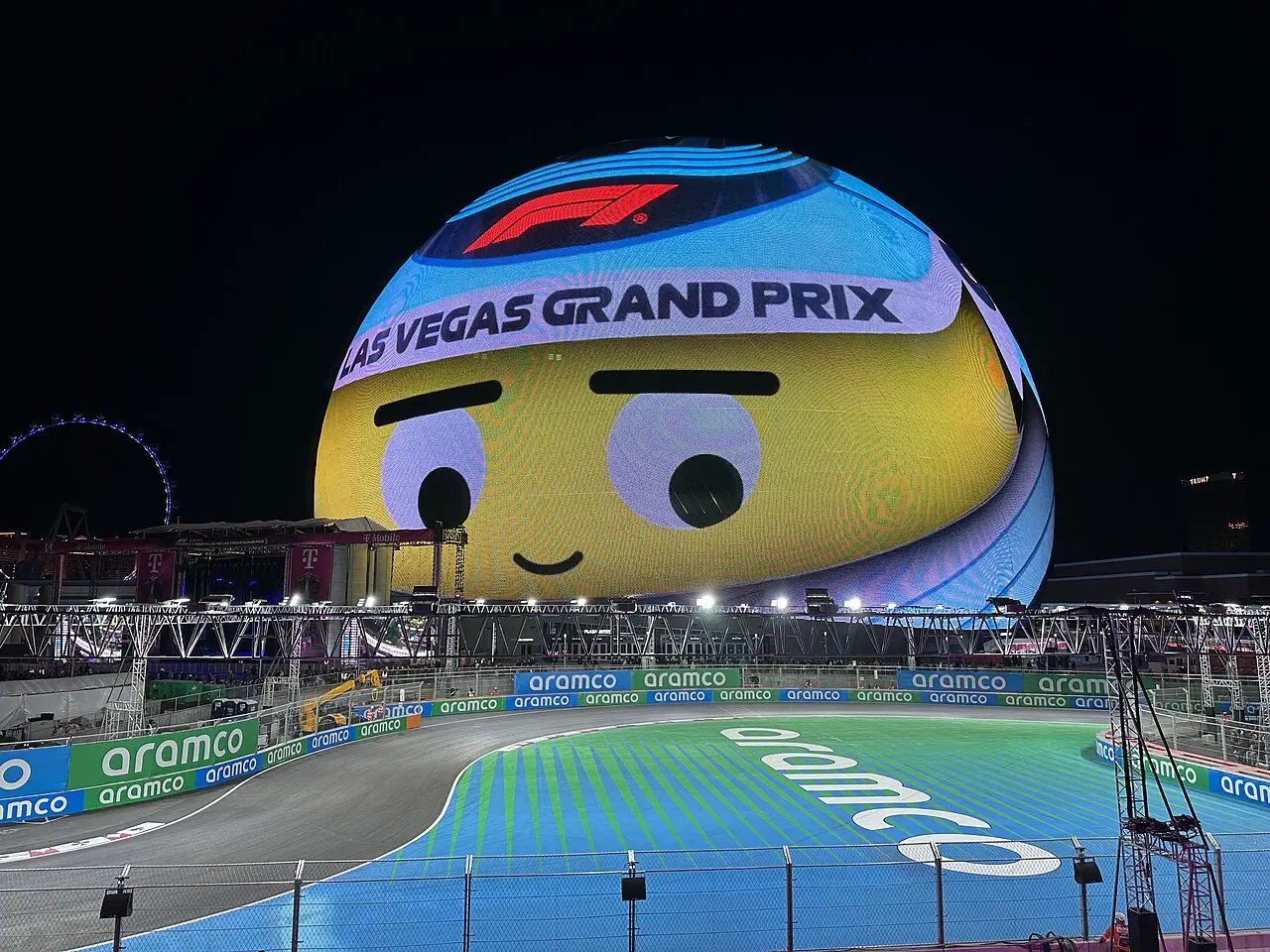Pista iluminada em azul e verde diante da Sphere, que exibe o logotipo do Las Vegas Grand Prix e o da Fórmula 1, à noite, em 2024.