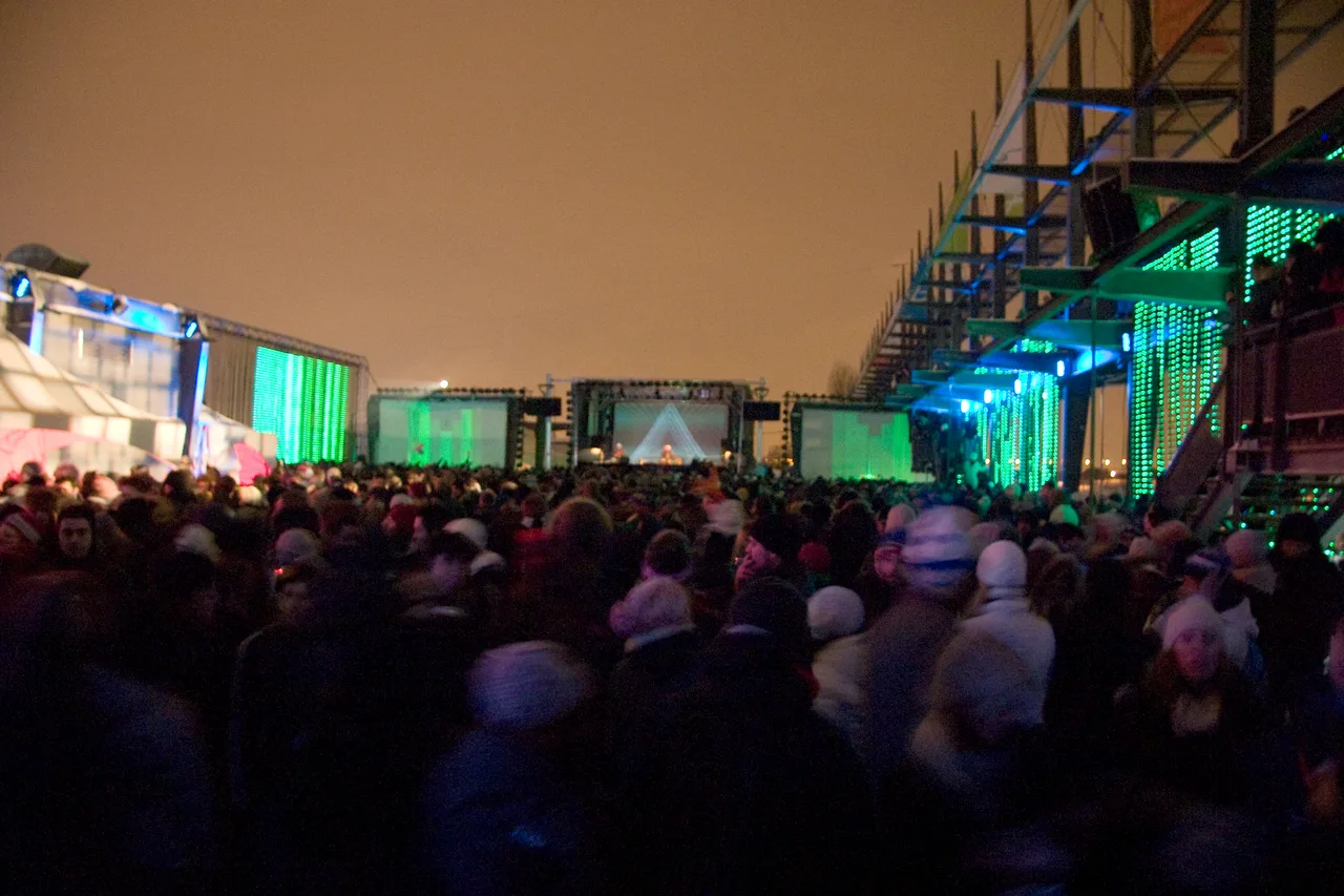 Multidão de costas, de gorro e casaco, diante de um palco ao ar livre à noite, no Igloofest de janeiro de 2009 em Montreal.