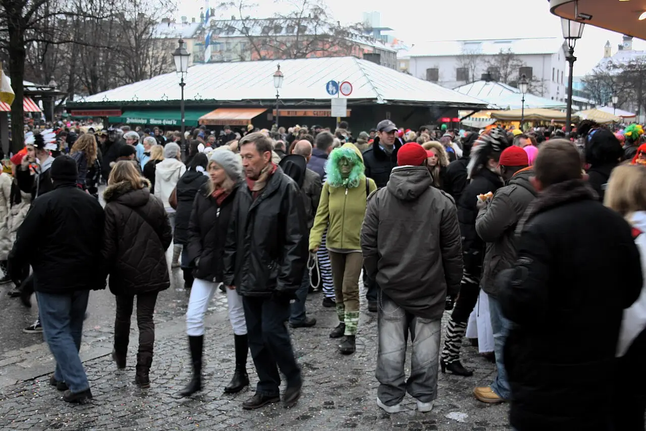 Gente atravessa a praça do mercado, entre tendas, e uma pessoa usa uma peruca verde.