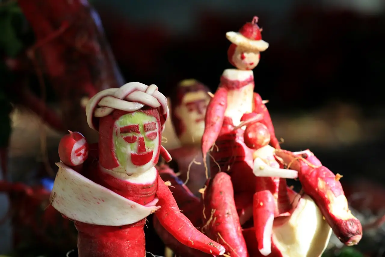 Rabanetes vermelhos esculpidos formam figuras humanas, uma com um toucado branco e outra de chapéu.