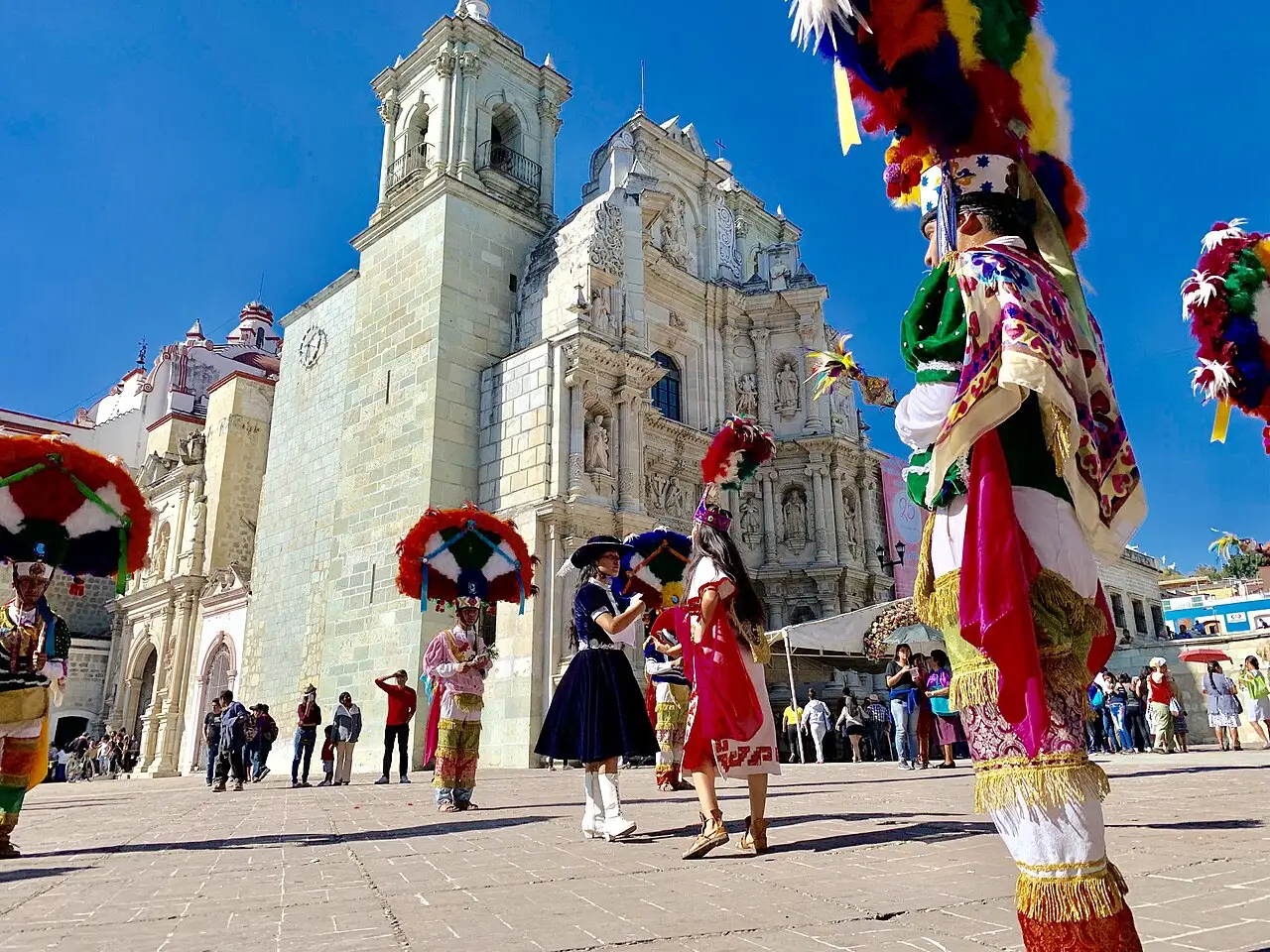 Dançarinos com penachos e trajes bordados numa praça de pedra, diante de uma igreja barroca, nas festas da Virgen de la Soledad em Oaxaca, em 18 de dezembro de 2018.