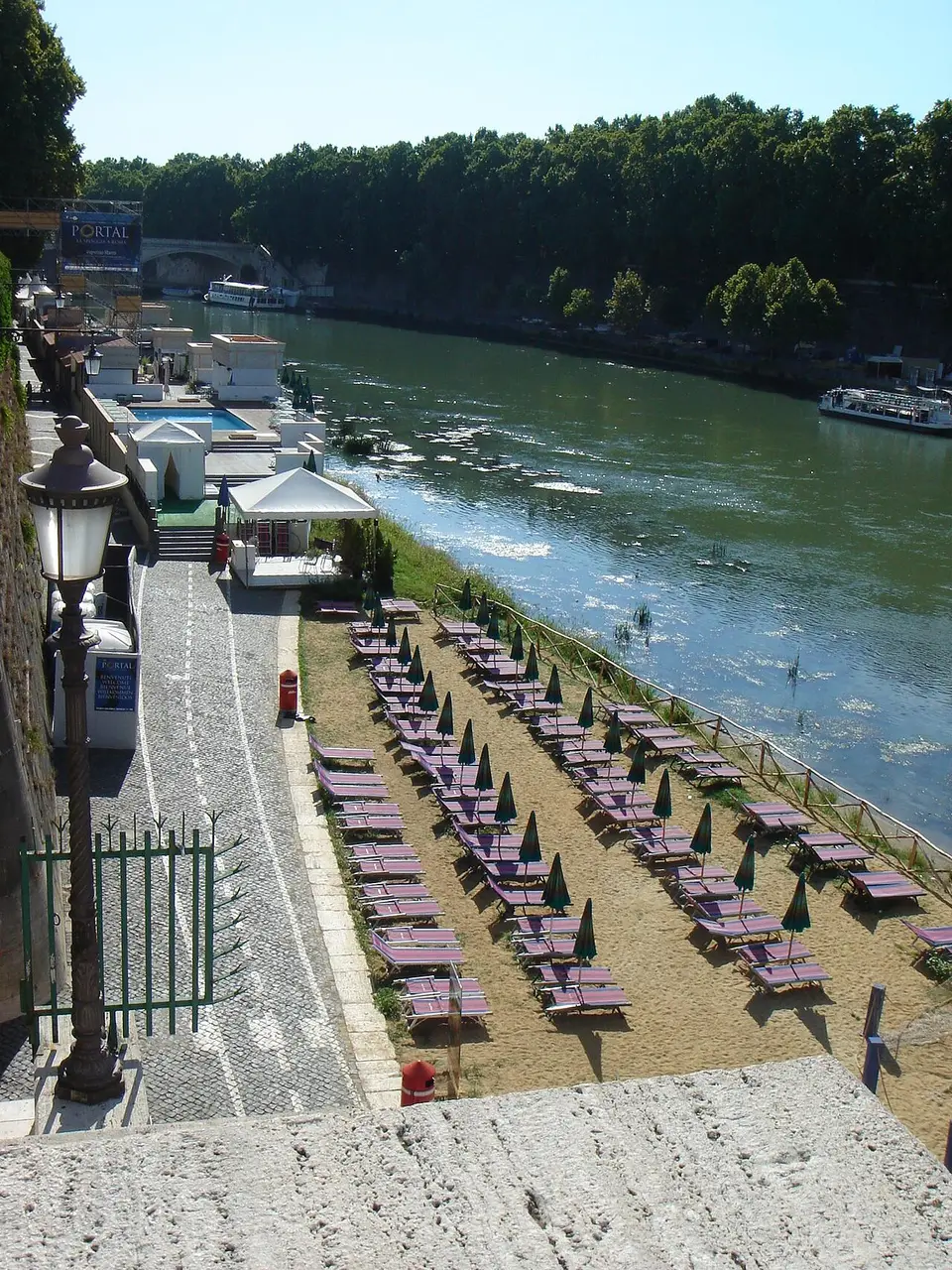 Fileiras de espreguiçadeiras e guarda-sóis fechados junto ao Tibre, perto do Castel Sant’Angelo, no verão de 2006.