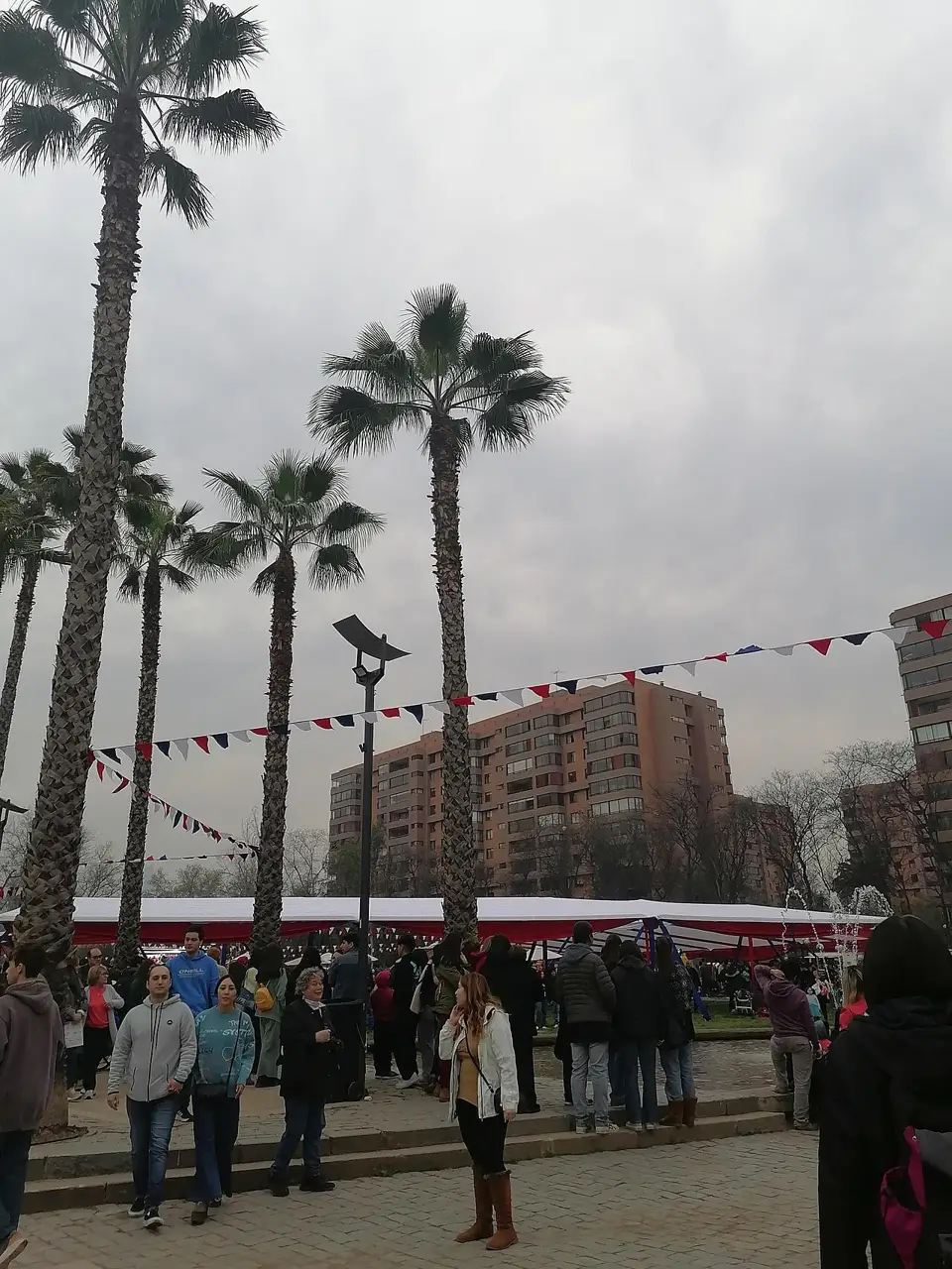 Parque com palmeiras, bandeirinhas vermelhas, brancas e azuis, barracas e gente, nas Fiestas Patrias em Santiago, em 18 de setembro de 2023.