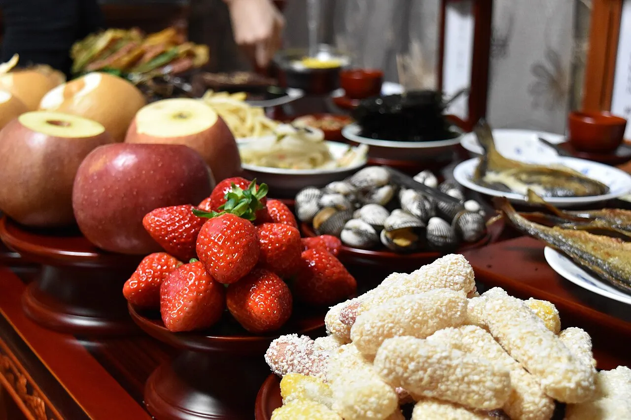 Frutas, peixe seco, marisco e bolinhos de arroz numa mesa baixa de madeira, para o rito do charye.