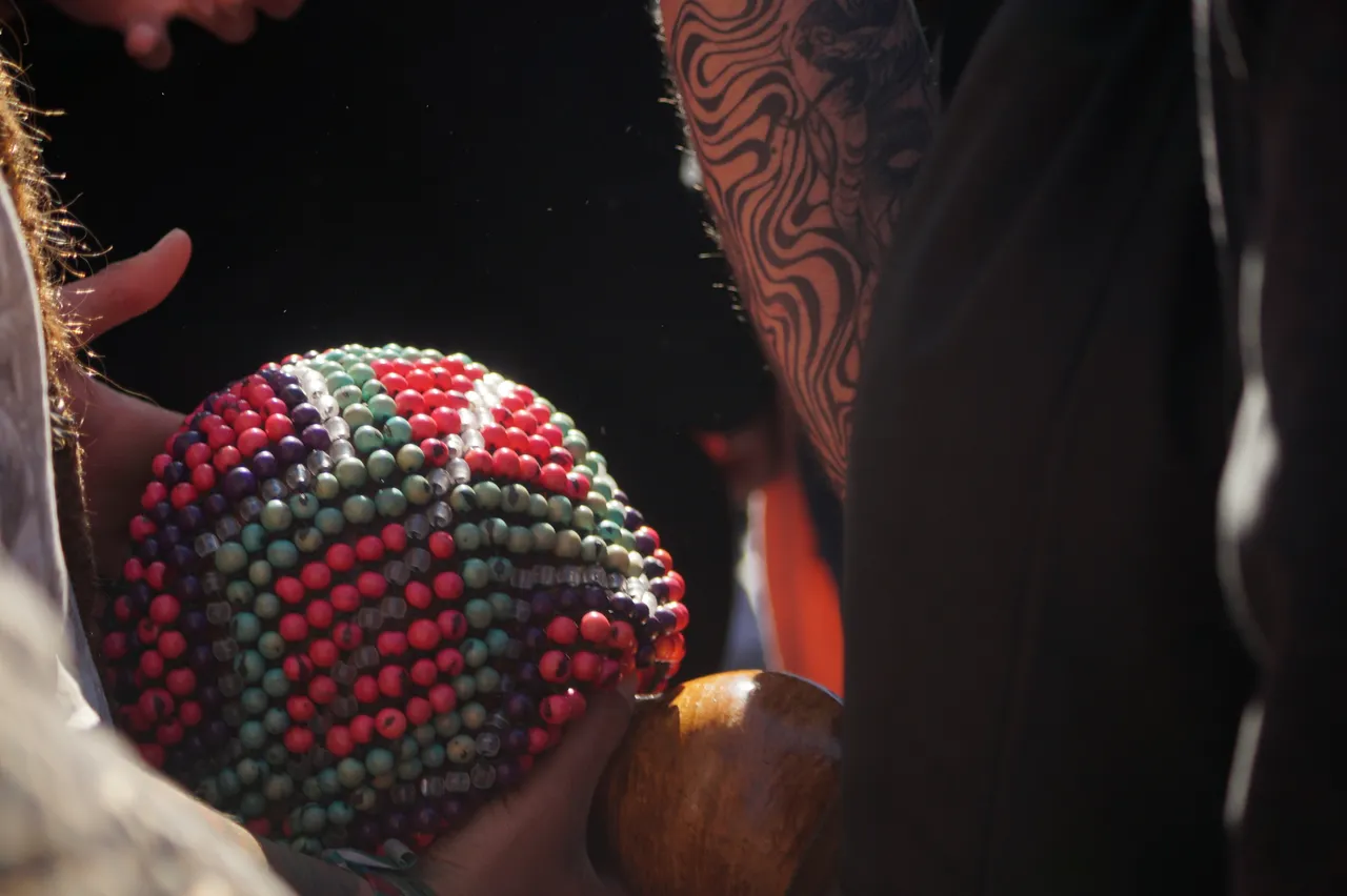 Uma esfera coberta de contas coloridas, presa a um cabo de madeira, é segurada de perto durante o Mil Tambores em Valparaíso.