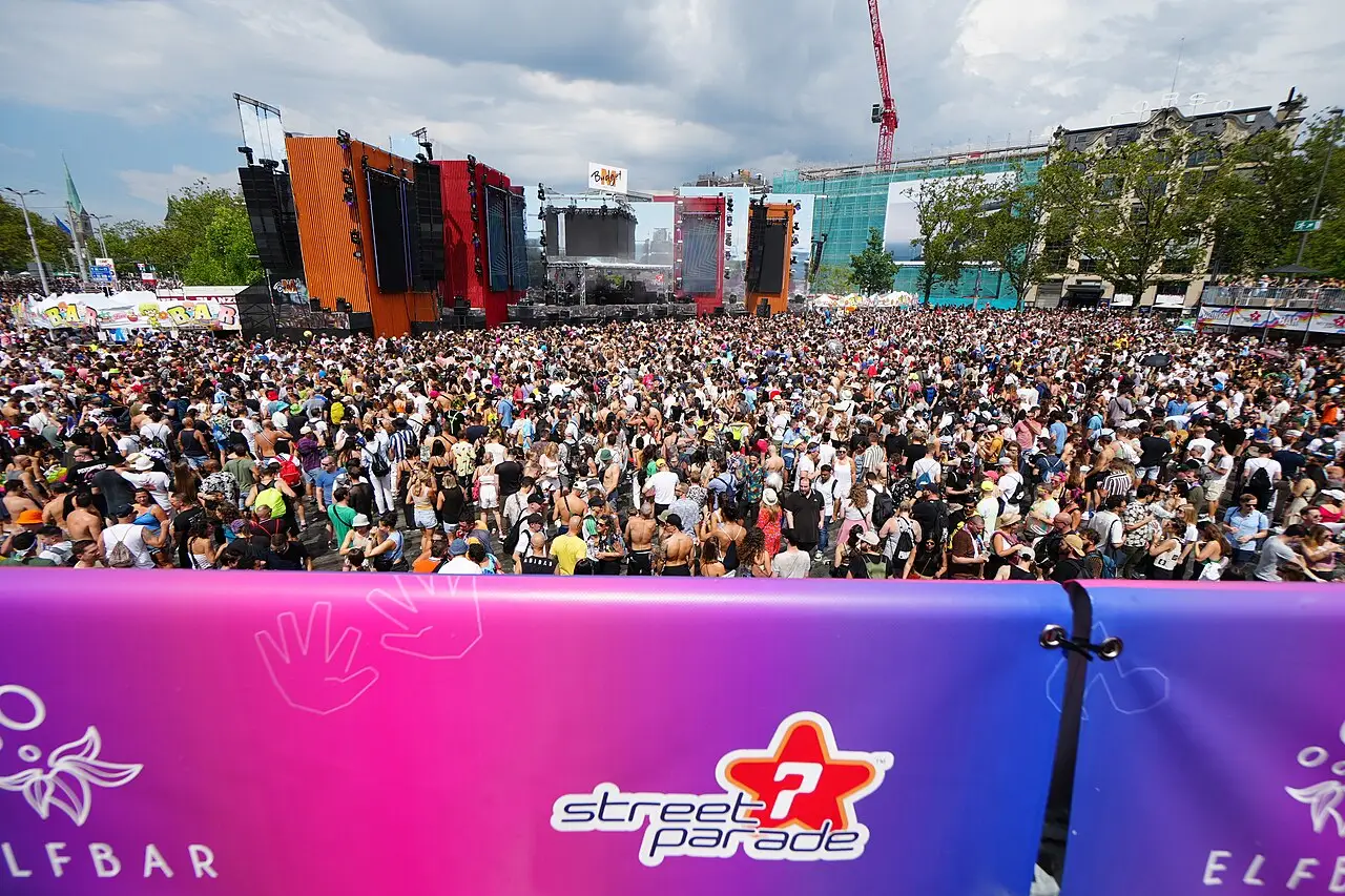 Uma multidão enche o espaço diante do palco, e a faixa na frente traz o nome Street Parade.