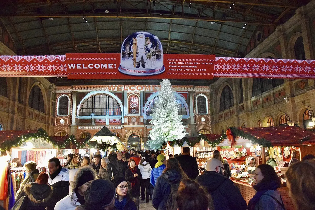 Dentro da estação, o público caminha entre barracas e uma árvore de Natal, sob a faixa de boas-vindas.
