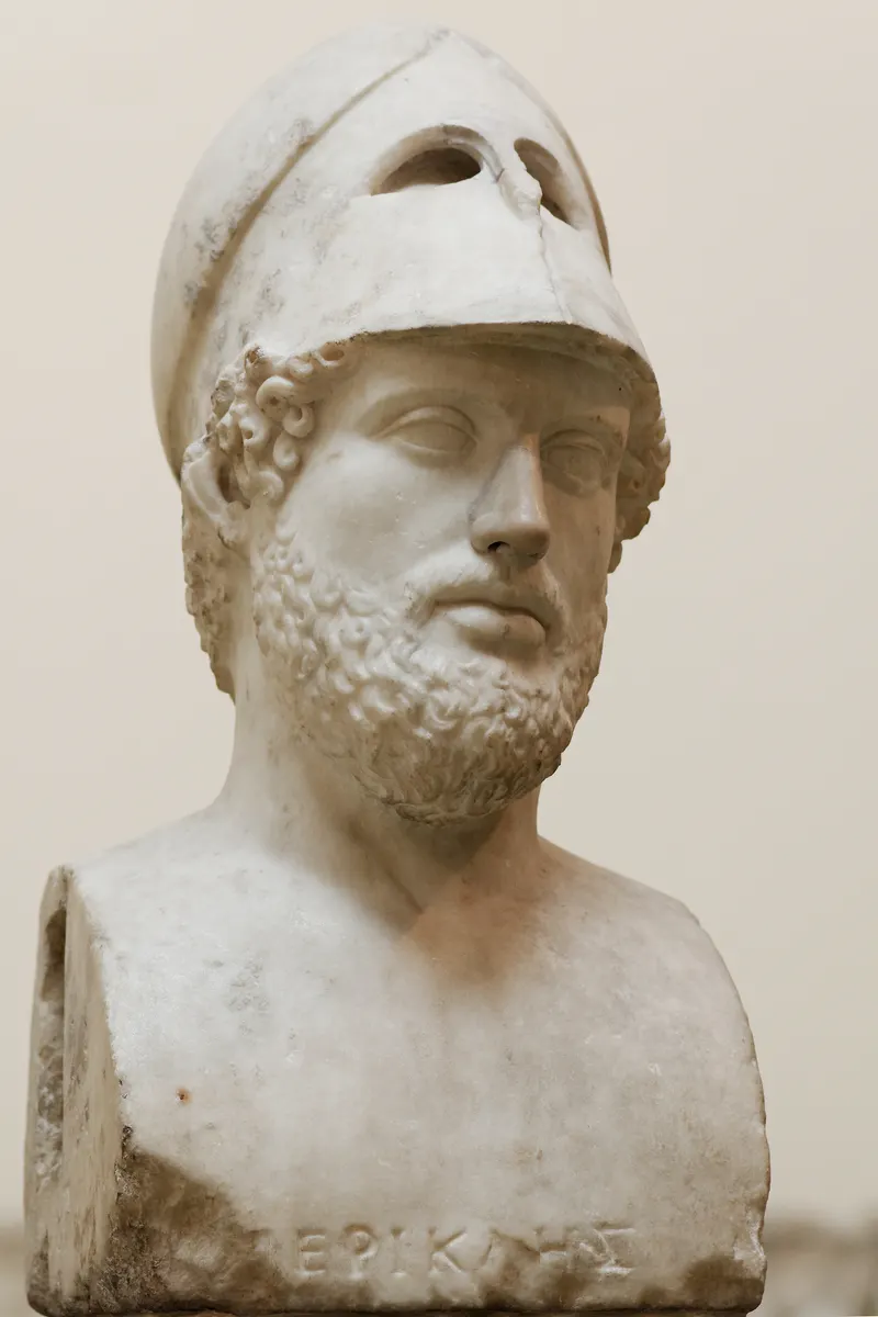 Busto de mármore de Péricles com barba, capacete erguido e inscrição grega na base.
