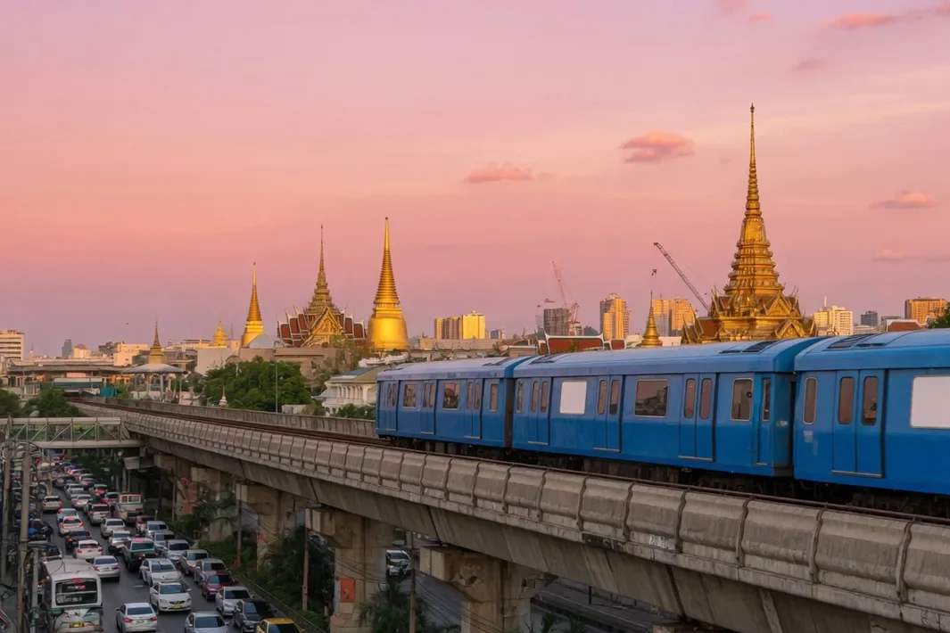 O trem azul no viaduto elevado, com as torres douradas e o céu rosa no meio.