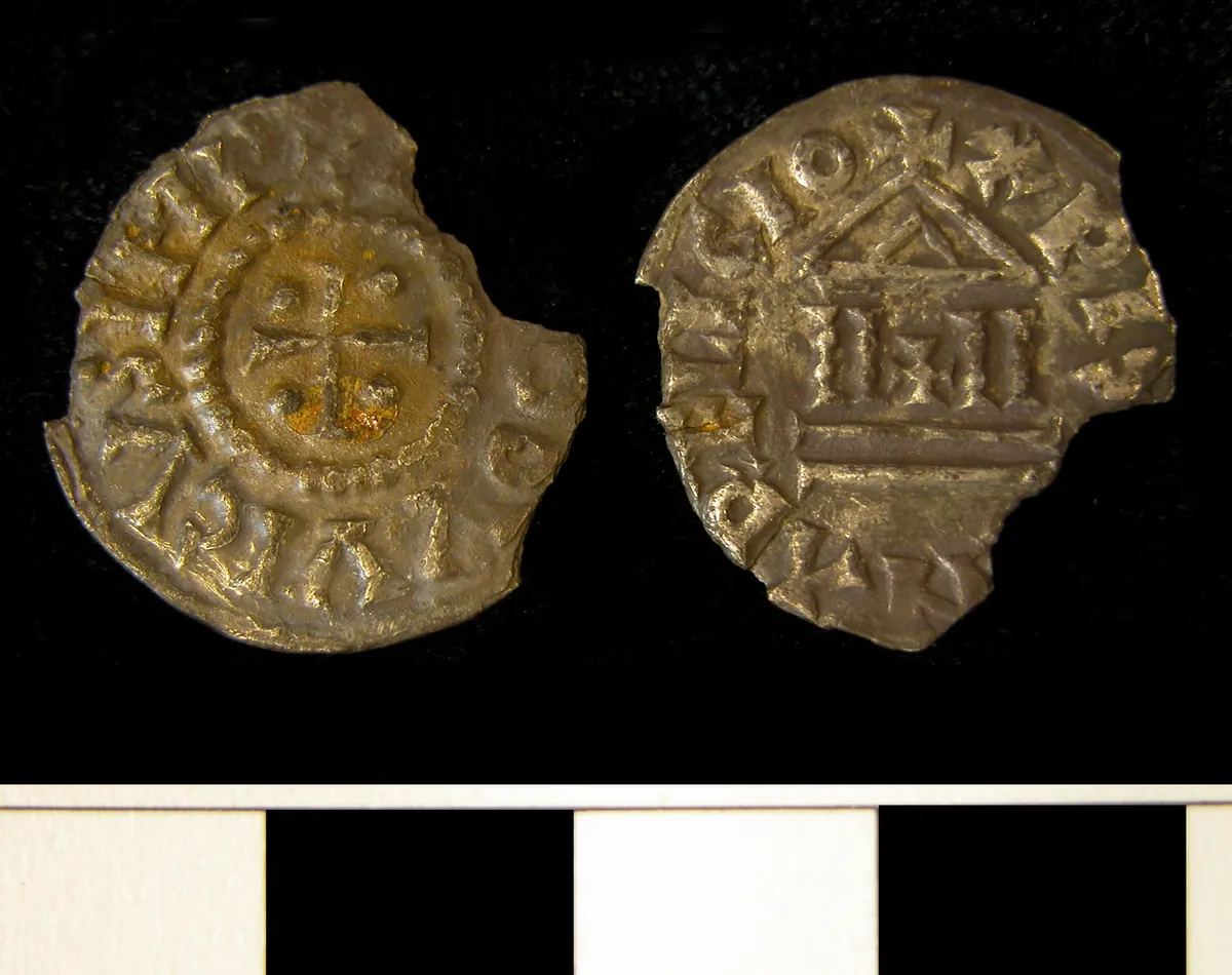 Duas faces de uma moeda fragmentada, com cruz, inscrições e edifício estilizado, sobre fundo claro com escala preta e branca.