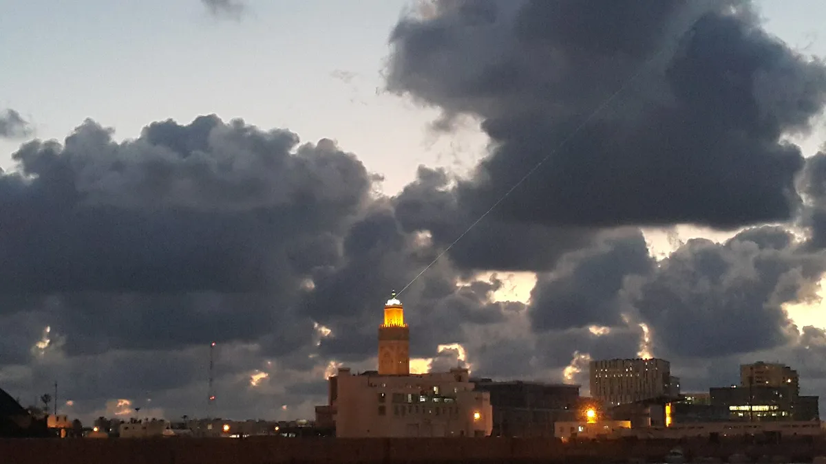 Um minarete iluminado sob nuvens escuras, no meio da cidade.