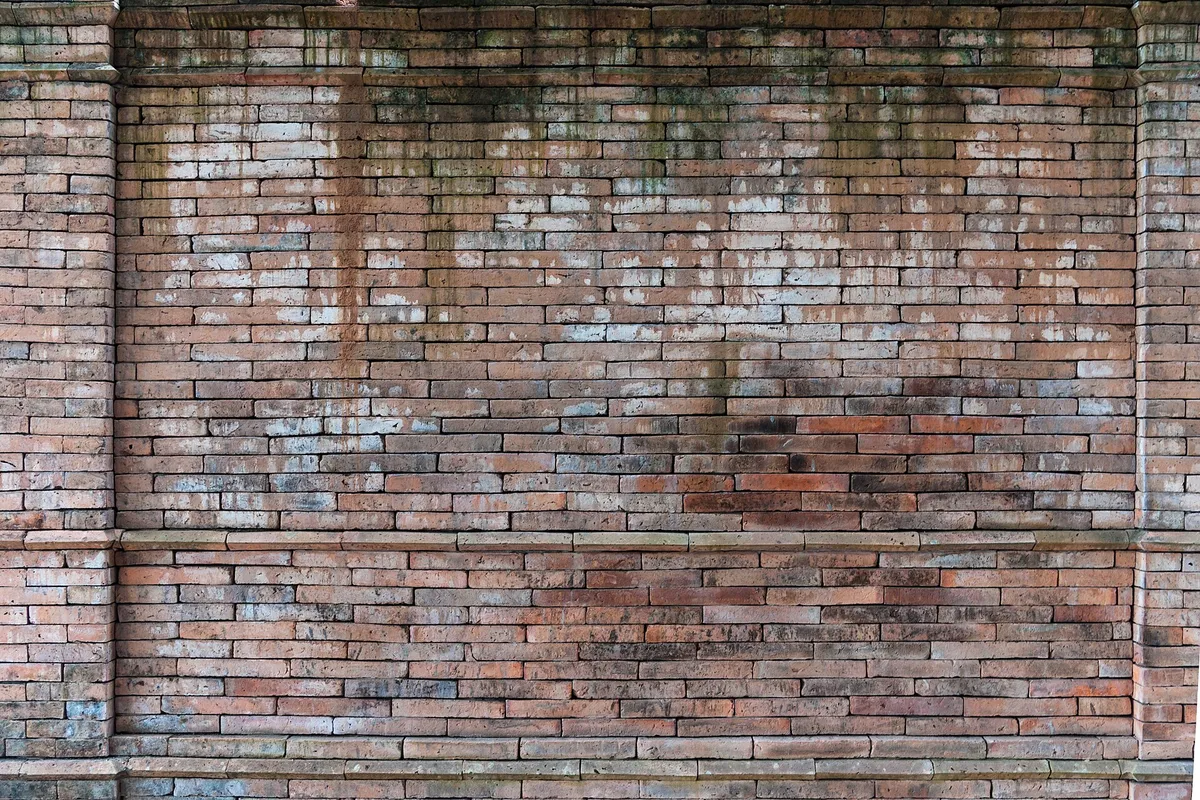 Muro de tijolos da cidade antiga, em faixas claras e escuras.