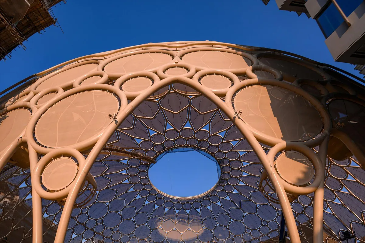 Cúpula bege vista de baixo, com anéis de tela e um óculo aberto para o céu. Um andaime aparece no canto.