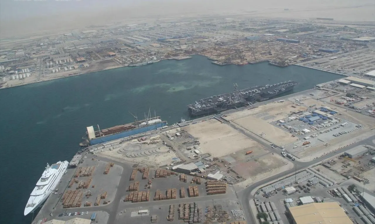 Vista aérea de um porto com navios atracados em cais longos, sem pessoas reconhecíveis.