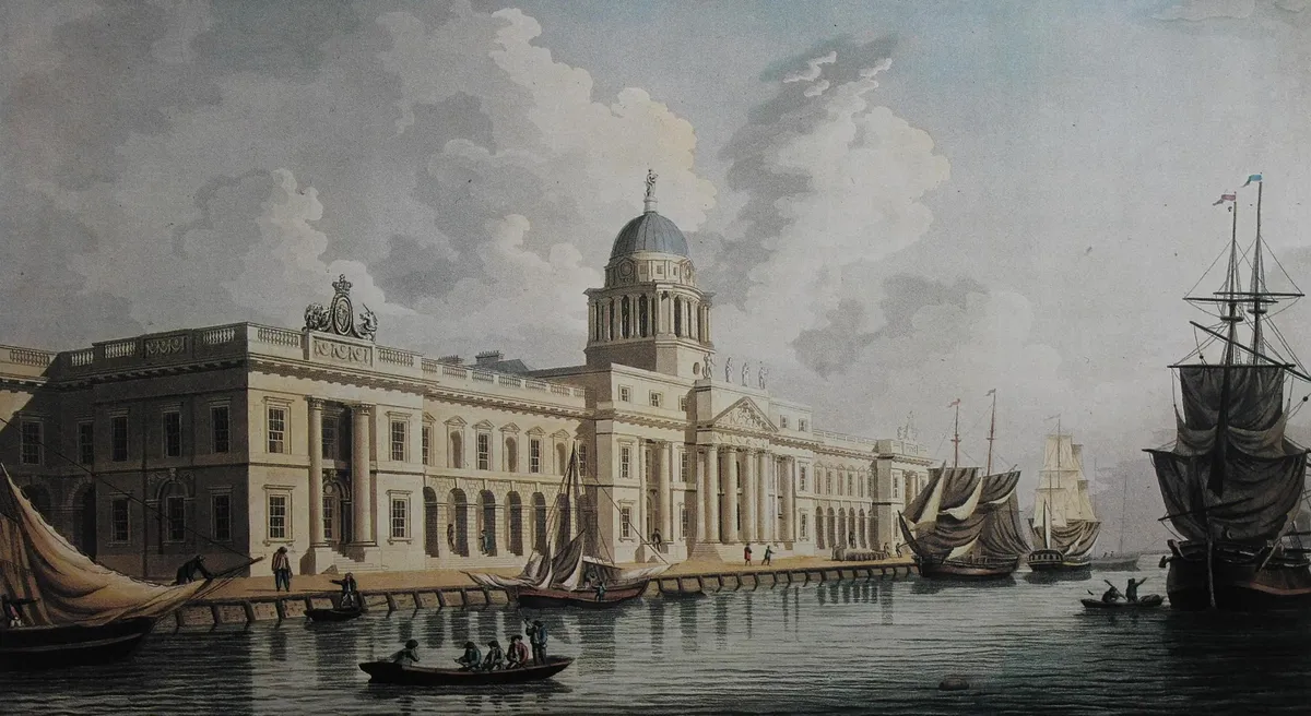 Engraving of the Custom House beside the Liffey, with dome, columns, boats and figures on the riverbank.