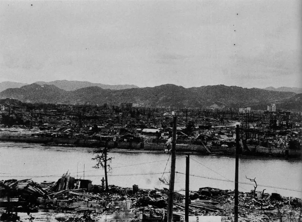Fotografia em preto e branco de Hiroshima vista do castelo, mostrando um bairro inteiro reduzido a escombros até a margem do rio, após a bomba atômica.