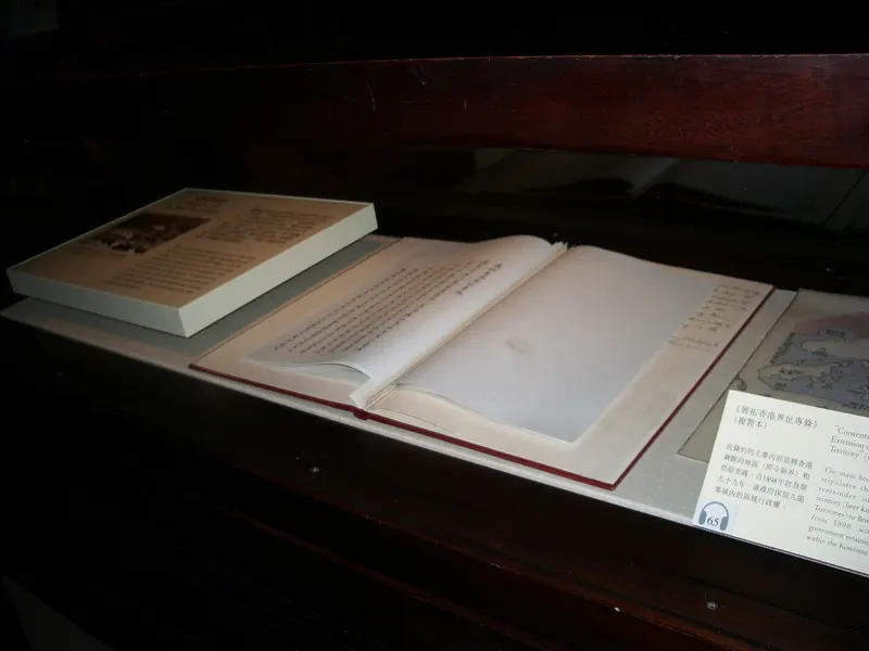 Um livro aberto numa vitrine escura, ao lado de uma etiqueta de museu.