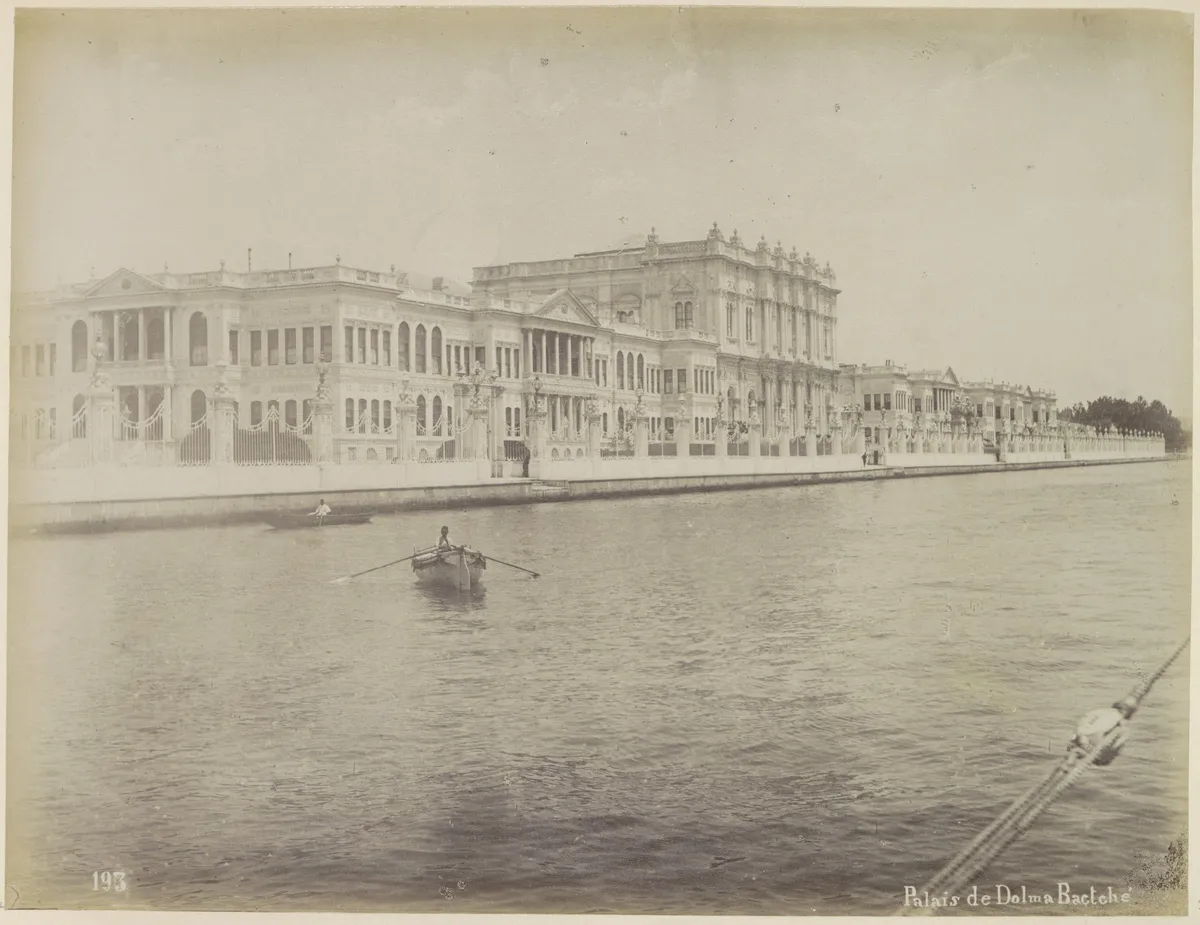 Fotografia sépia da fachada do palácio junto à água, com embarcações e remadores, margem de papel, número e título na parte inferior.